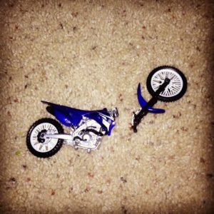 A broken dirt bike toy that is snapped in half