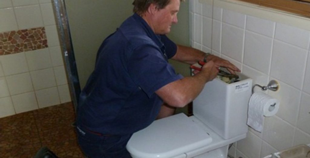 Example of a plumber fixing a commercial toilet.