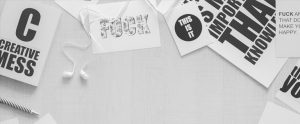 Graphic design posters laying on a white desk with white Samsung earbuds